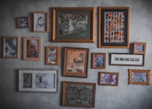 A collection of framed whimsical art pieces hanging on a warm-toned wall.