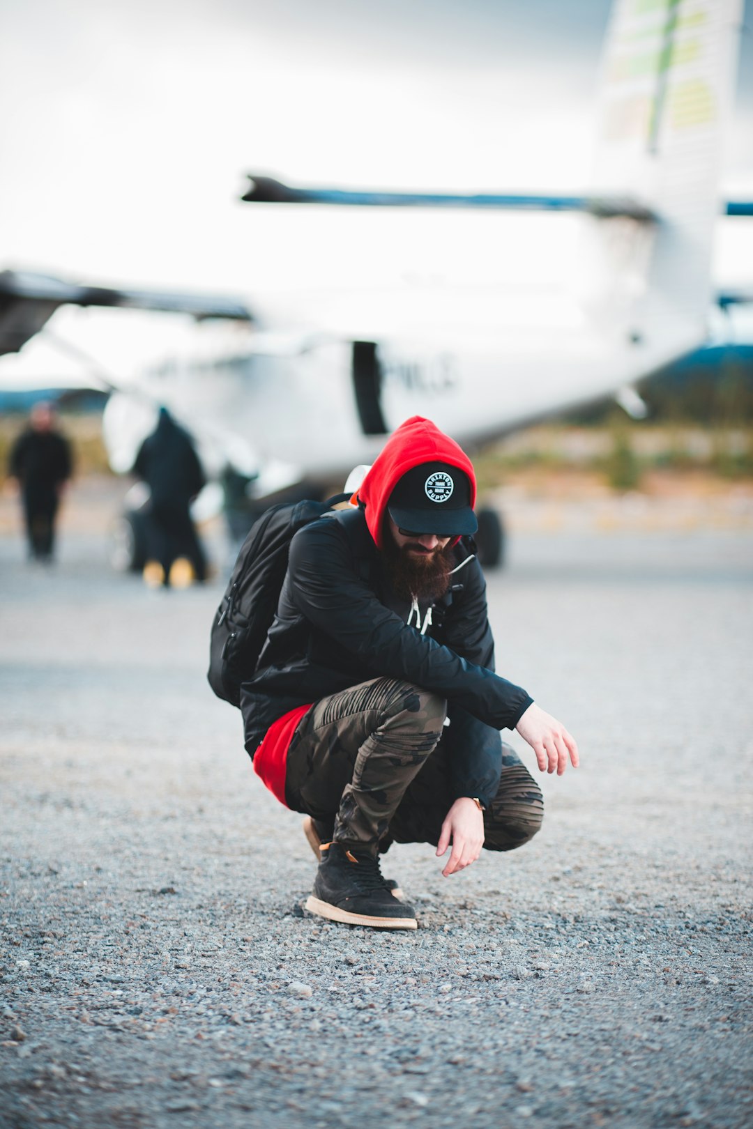 man in black jacket and red knit cap running on the street during daytime