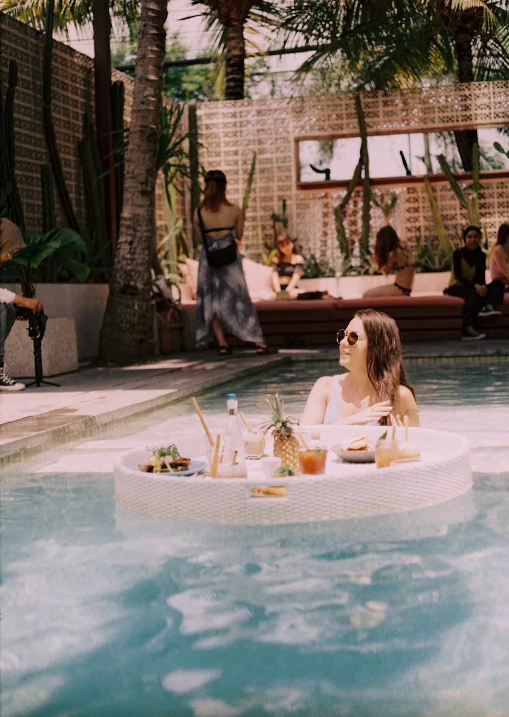 woman in white shirt sitting on chair near swimming pool during daytime