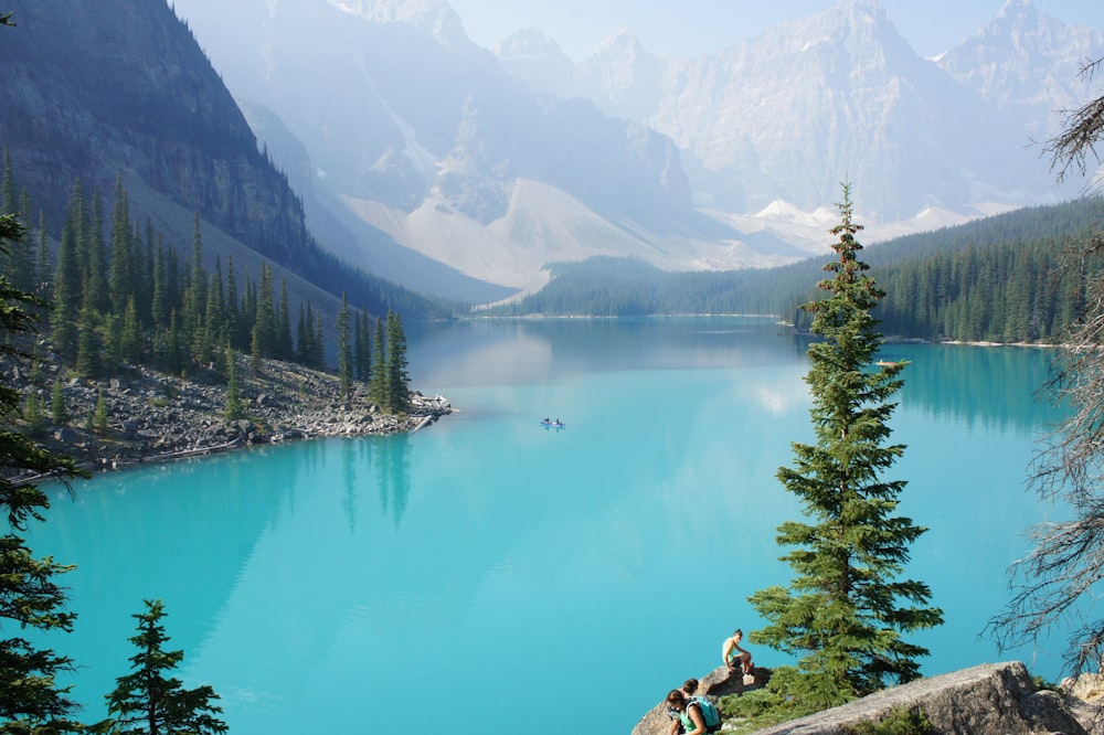 a group of people sitting on top of a mountain next to a lake