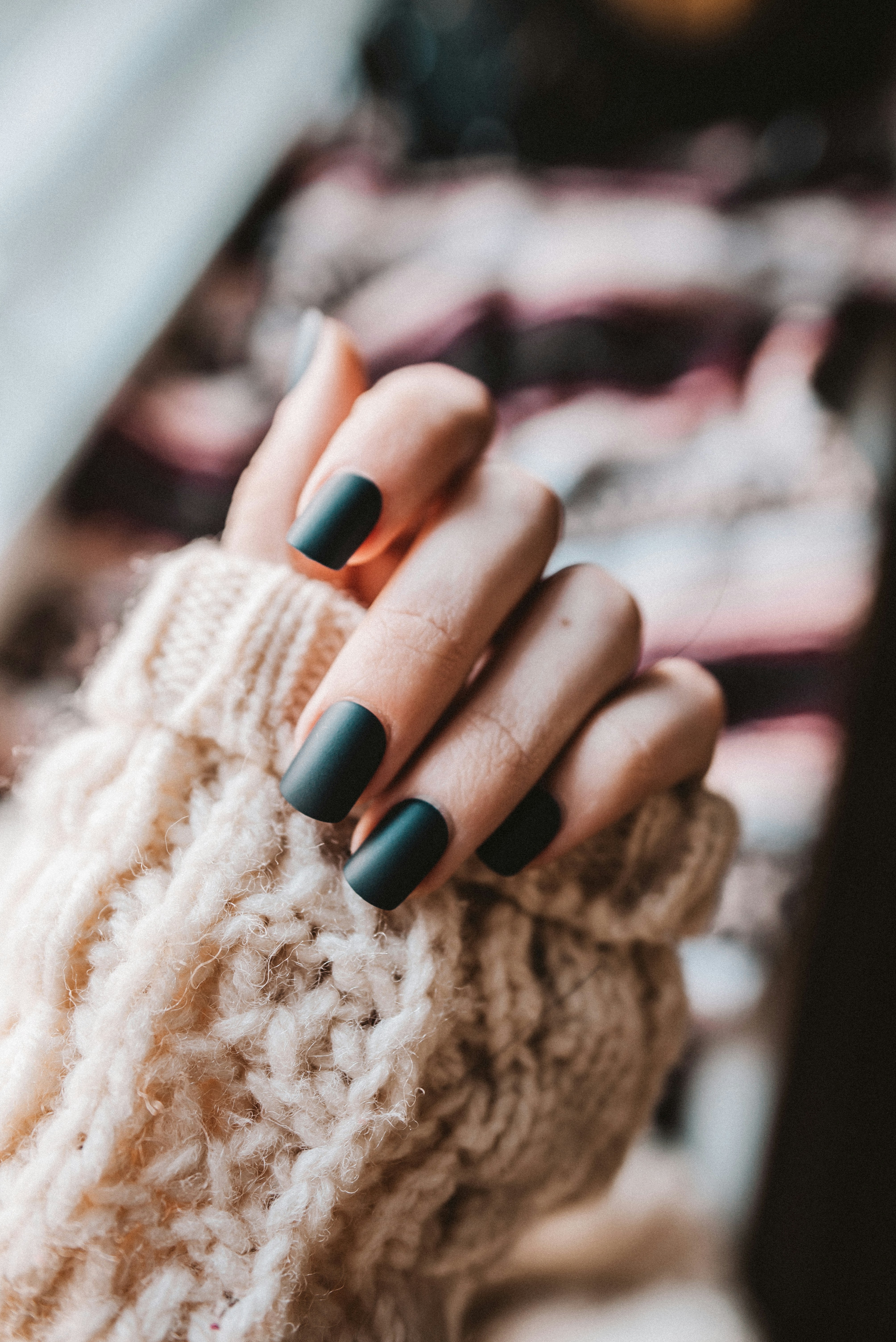 person with black manicure holding white textile