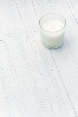 A clean, minimalist white candle with a subtle eucalyptus scent, set against a light background.