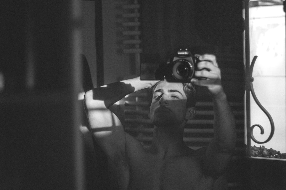 topless man holding black camera