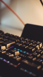 Close-up of a mechanical keyboard with blue ambient lighting reflecting on the keys.