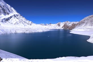 snow covered mountains near lake during daytime