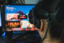 person wearing black headphones in front of black flat screen computer monitor