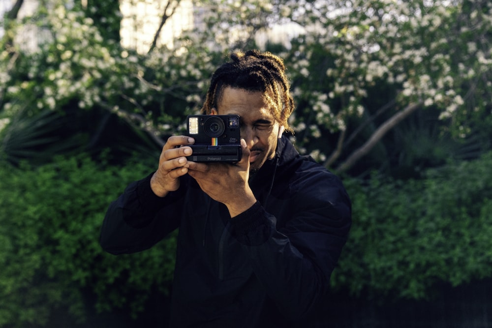 man in blue jacket holding black and red camera