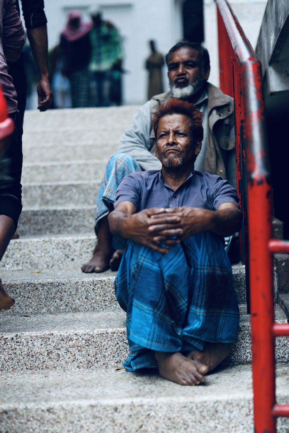 man in blue and black plaid button up shirt sitting on concrete stairs