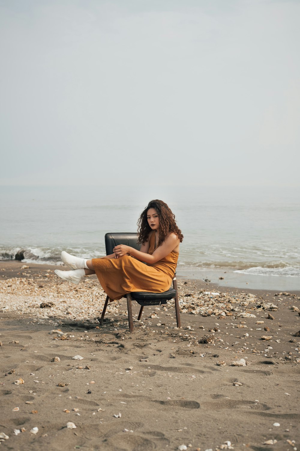 woman in brown long sleeve shirt sitting on chair on beach during daytime