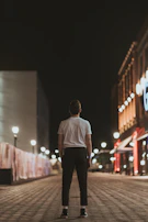 Mark standing alone on an empty city street at night, bathed in the warm glow of a streetlamp.
