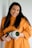 woman in orange sweater holding black and white camera