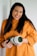woman in orange sweater holding black and white camera