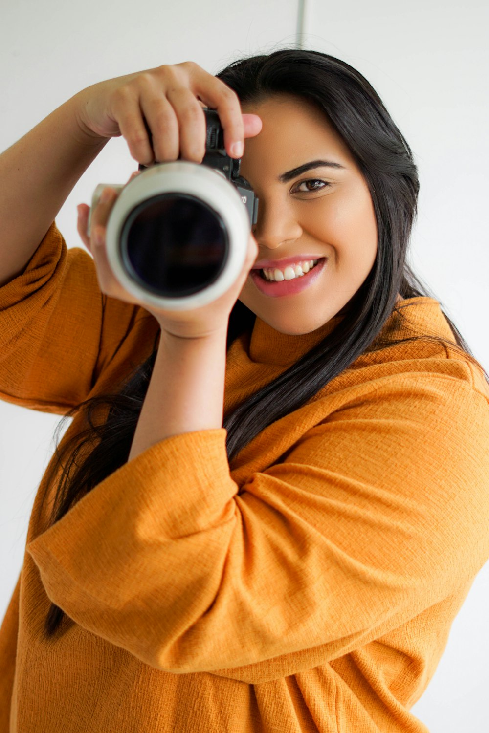 mulher no suéter laranja que segura a caneca de cerâmica branca