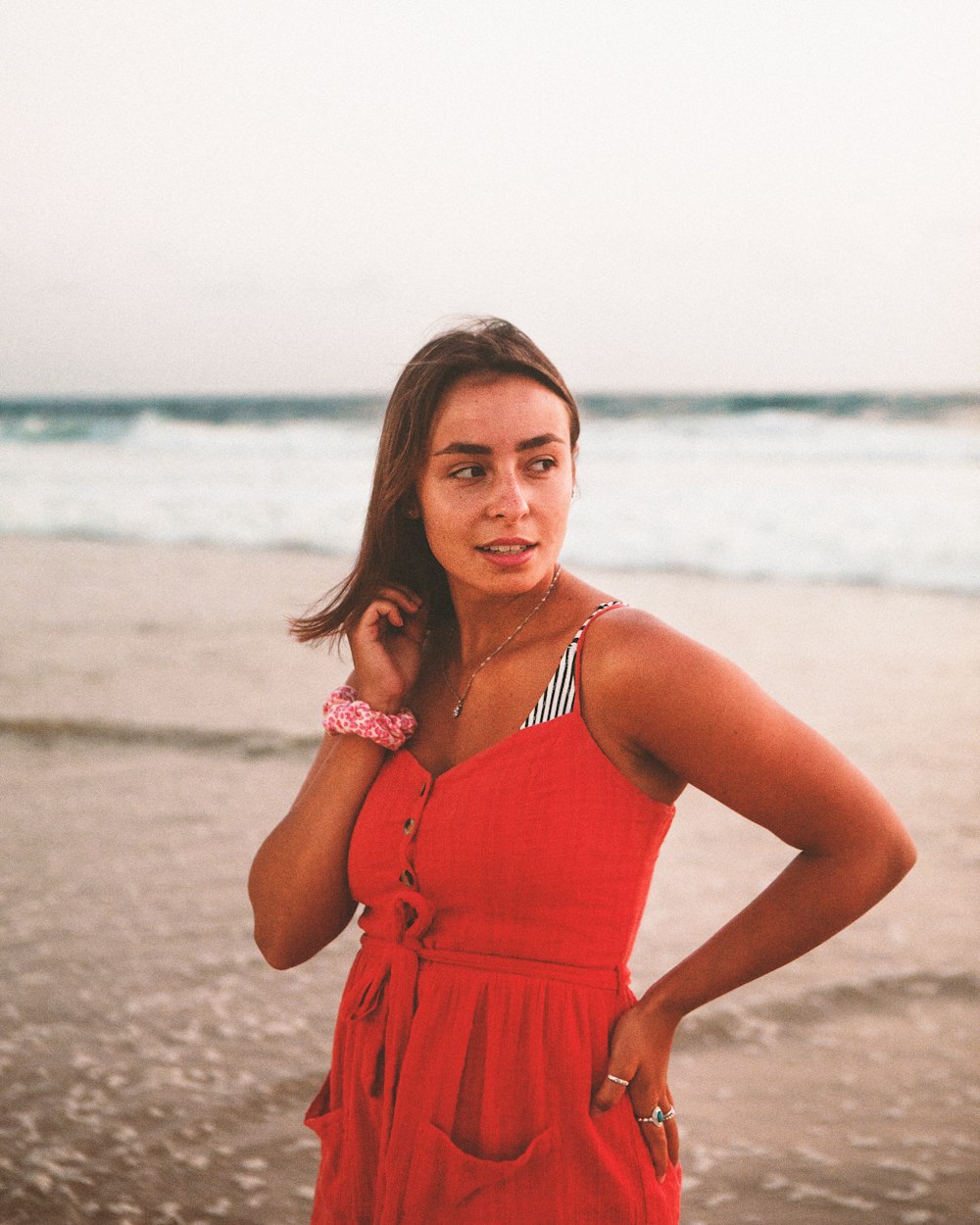 mulher no vestido vermelho da alça do espaguete que está na praia durante o dia