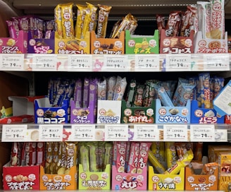 Selection of packaged snacks and treats stacked on a colorful store shelf.