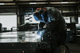 Close-up of a skilled welder working on a large pressure vessel in an industrial workshop.