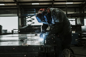 A welder in protective gear skillfully operating welding equipment in a metal workshop.