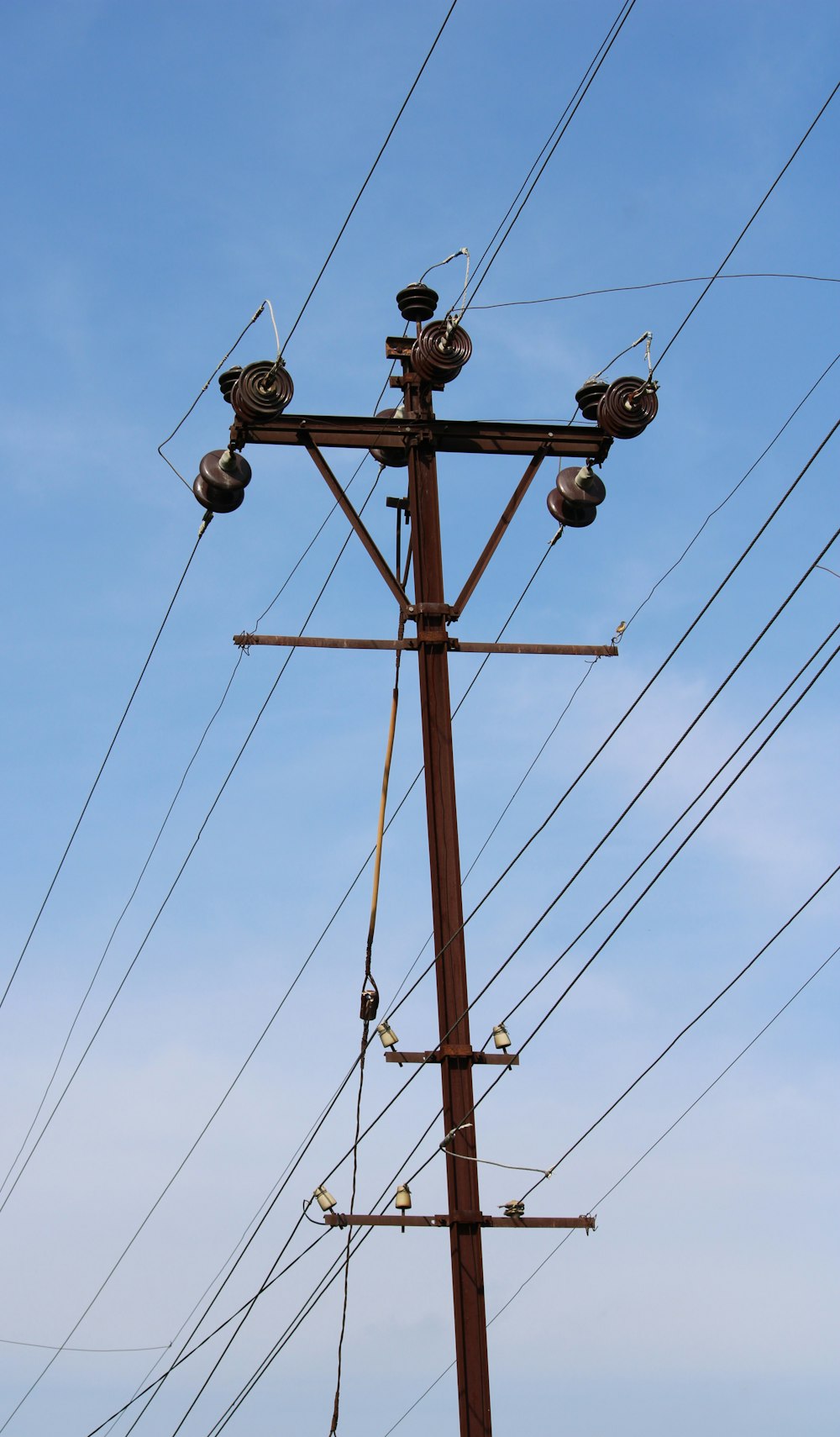 brown wooden electric post under blue sky during daytime