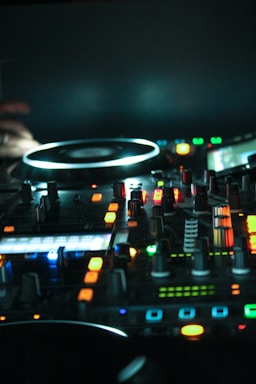 A sleek DJ console glowing under moody blue and purple lights in a dark club setting.
