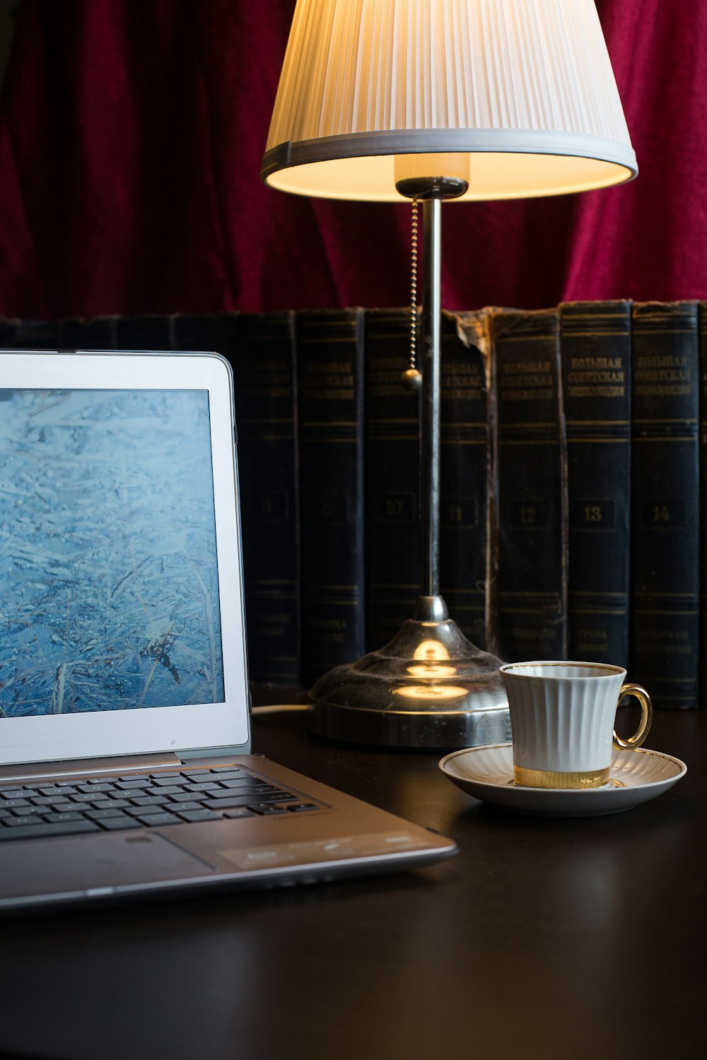 white ceramic mug on saucer beside black laptop computer