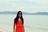 woman in orange sleeveless dress standing on beach during daytime