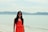 woman in orange sleeveless dress standing on beach during daytime
