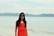woman in orange sleeveless dress standing on beach during daytime