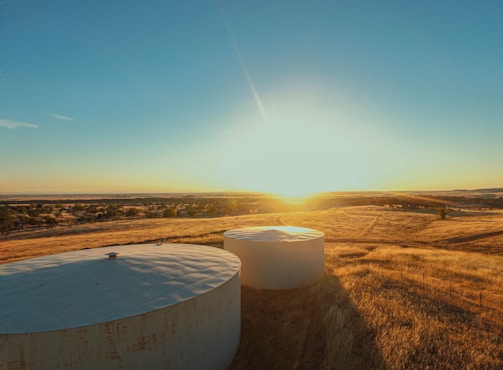 An agricultural propane tank being refilled on a sunny farm field.
