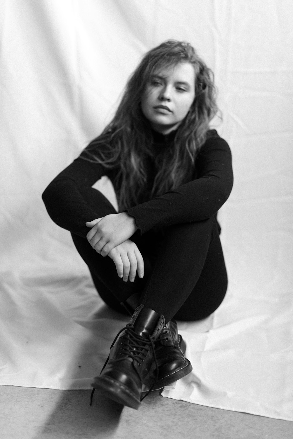 woman in black long sleeve shirt and black pants sitting on white textile