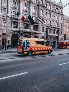 white and red ambulance on road near buildings during daytime