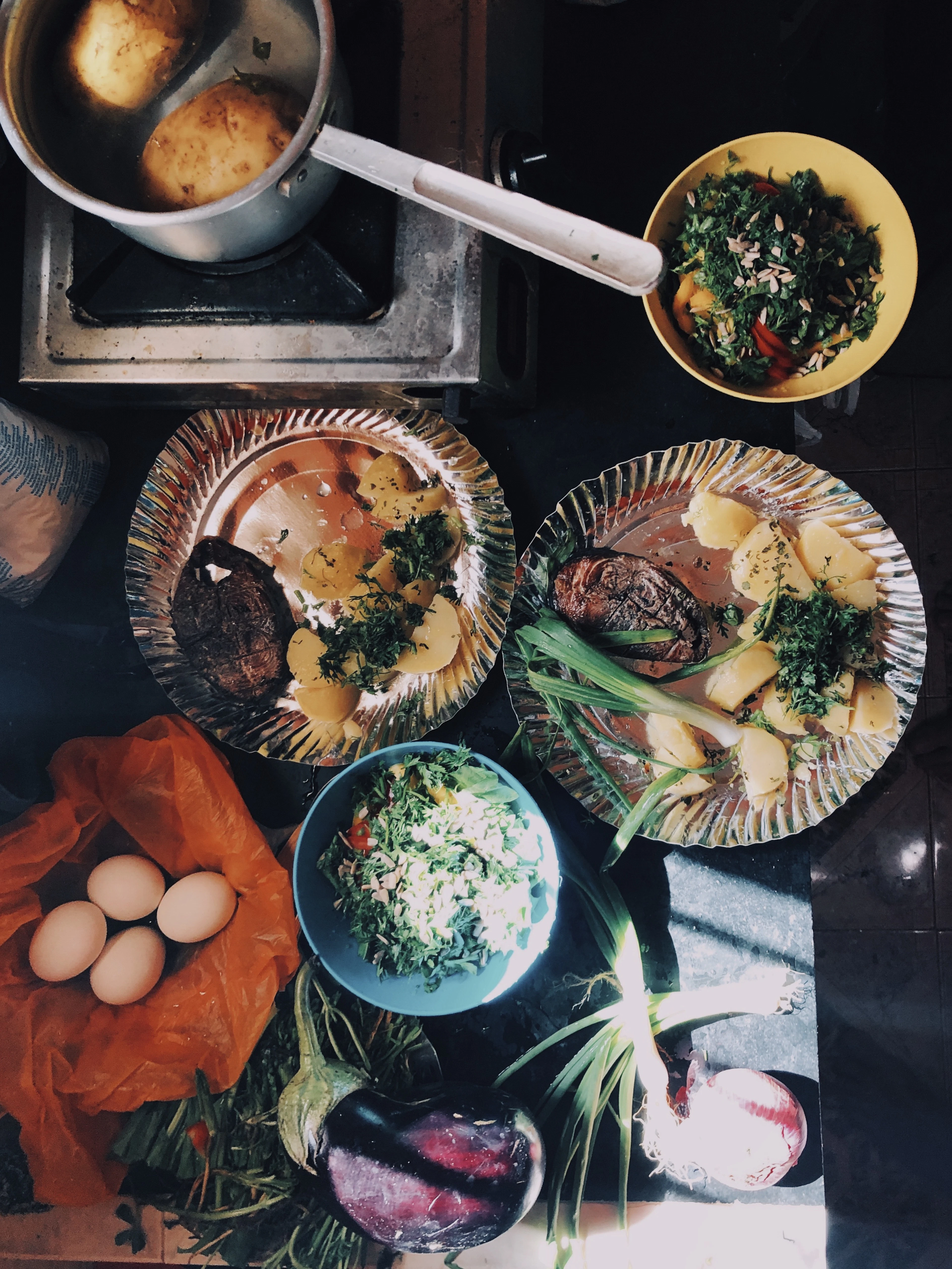 An overhead view of a home-cooked meal spread in Goa with curry, rice, boiled eggs and fresh greens.