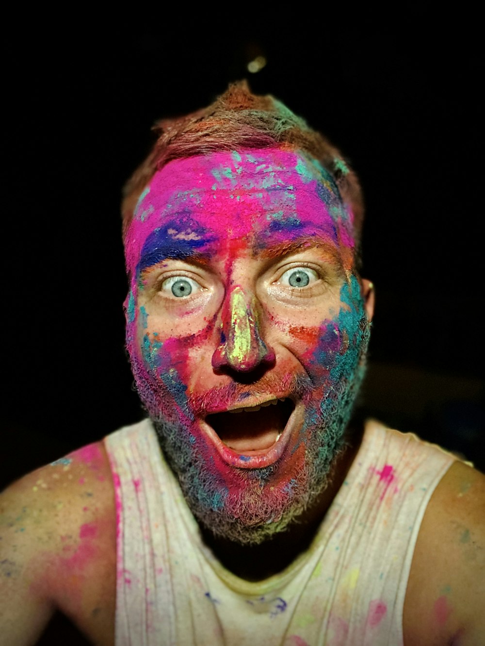 hombre en camiseta sin mangas blanca con pintura rosa y azul en la cara