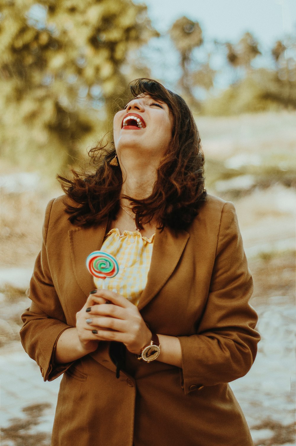 woman in brown coat holding white and red cup