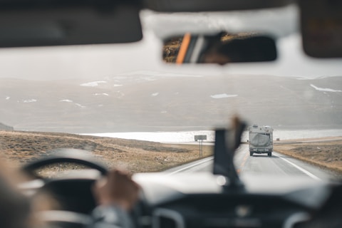 a bus driving down a road next to a mountain