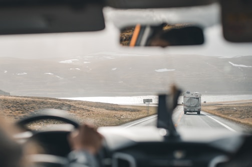 a bus driving down a road next to a mountain