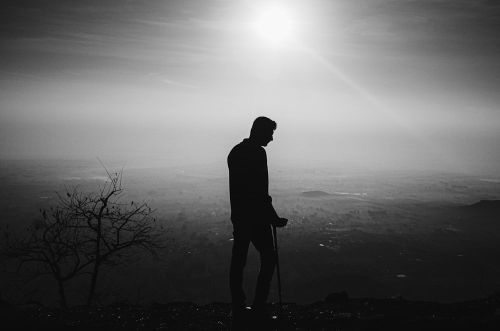 silhouette di uomo in piedi vicino all'albero nudo durante il giorno