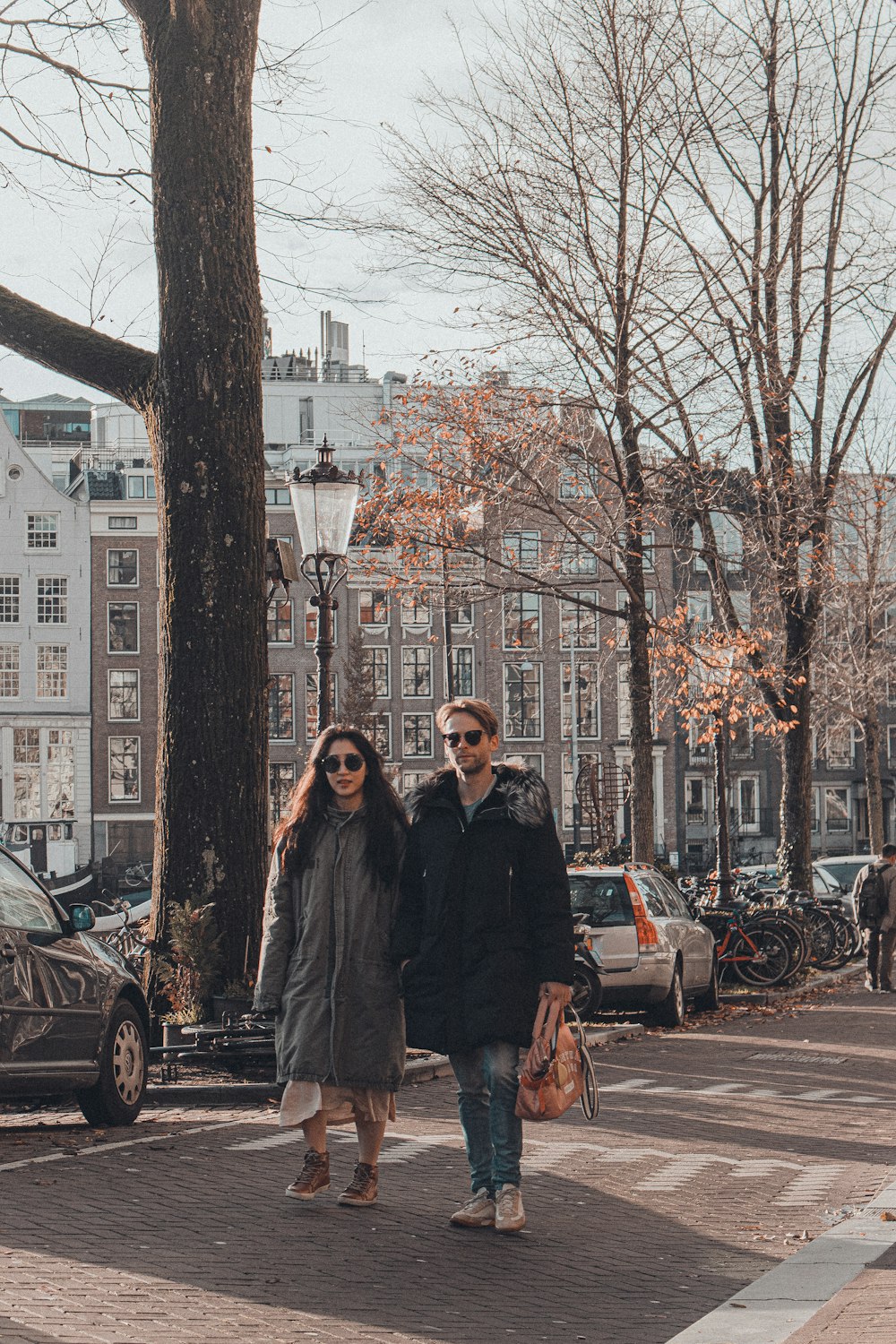 man and woman standing beside bare tree during daytime