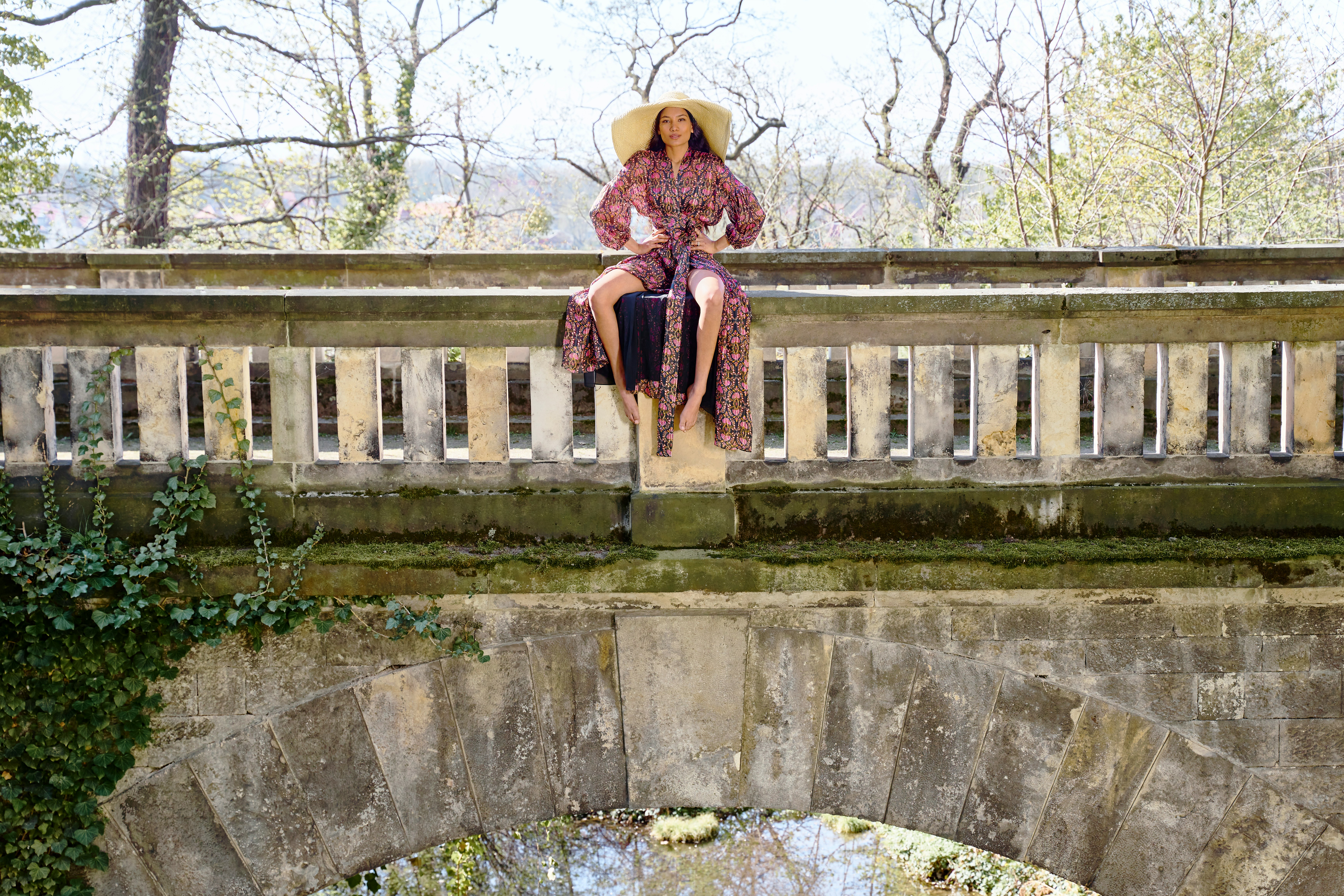 woman in brown sun hat standing on gray concrete bridge during daytime