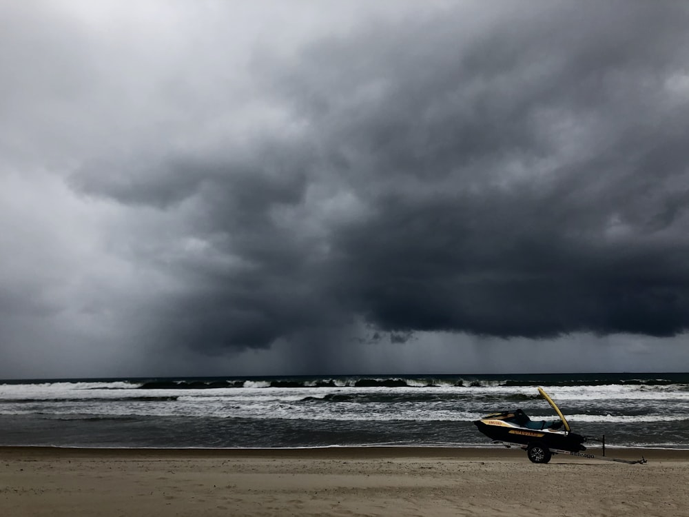 brown boat on beach shore under gray clouds