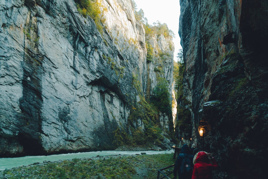 person in red jacket standing near gray rock formation during daytime