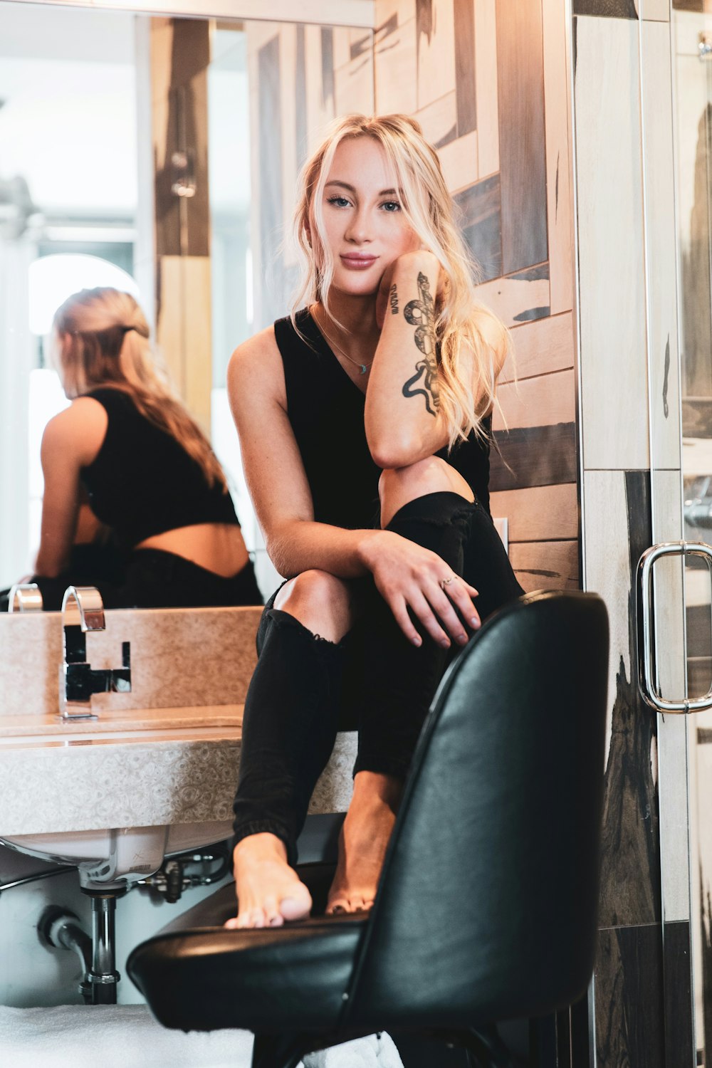 woman in black tank top and black pants sitting on black leather chair