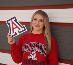 a girl in a red sweatshirt holding up a sign