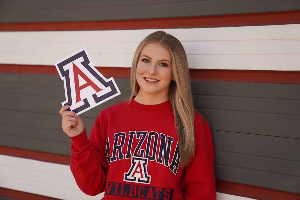 a girl in a red sweatshirt holding up a sign