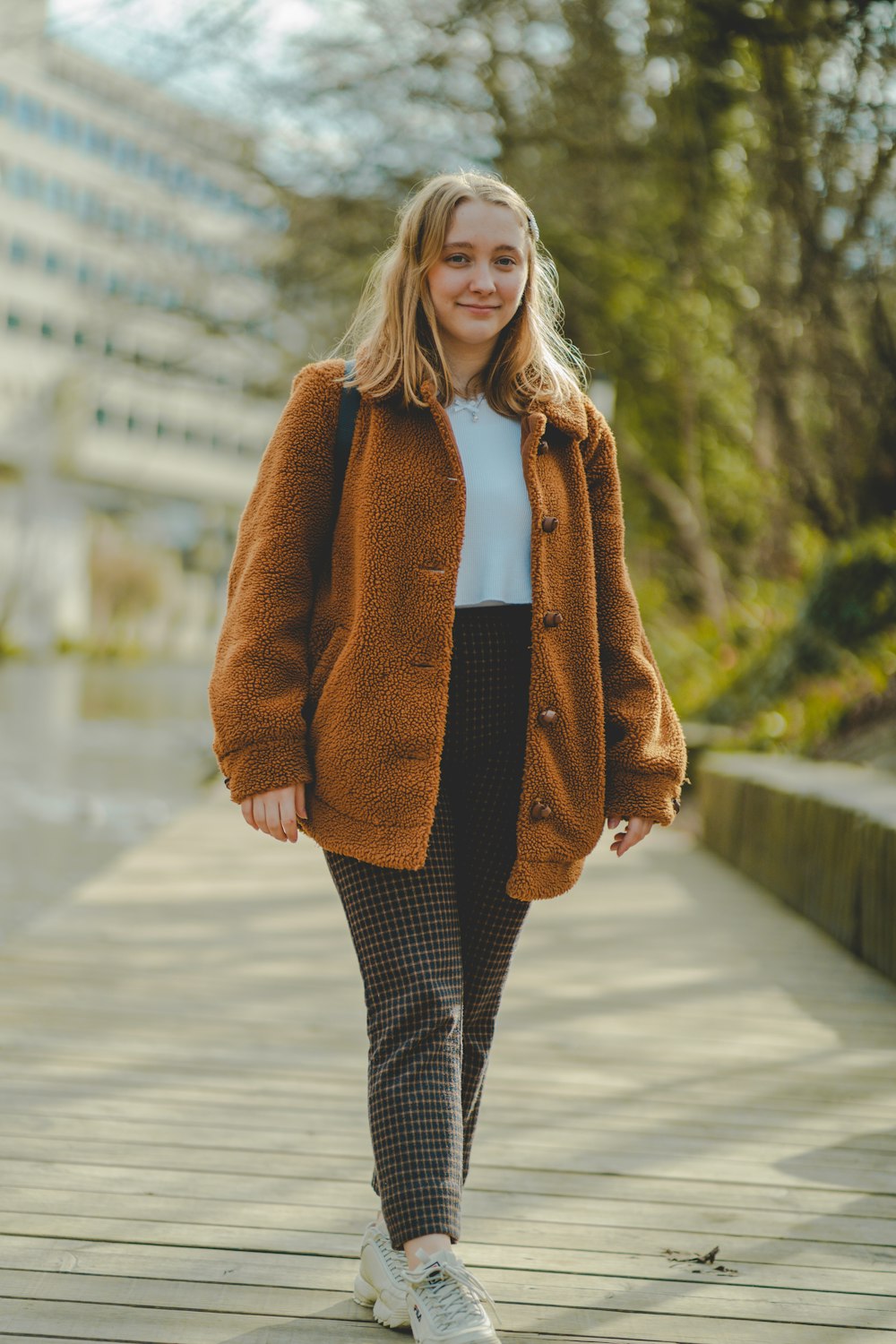 woman in brown coat standing on road during daytime