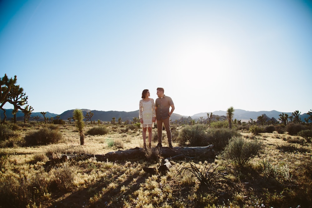 man and woman holding hands while walking on dirt road during daytime