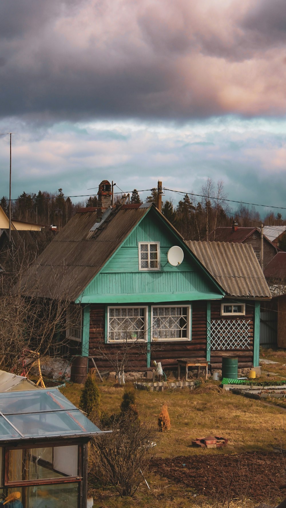 brown wooden house near bare trees under cloudy sky during daytime