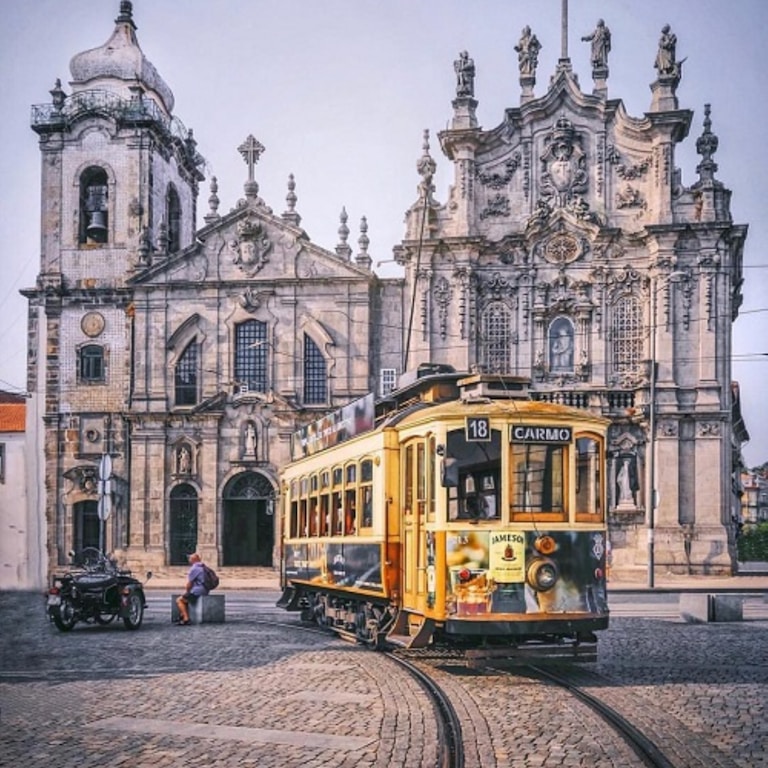 yellow tram in front of gray concrete building in Porto, Portugal