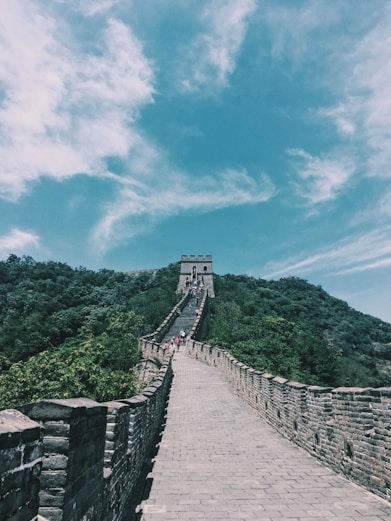 people walking on wooden bridge over green mountain under blue sky during daytime