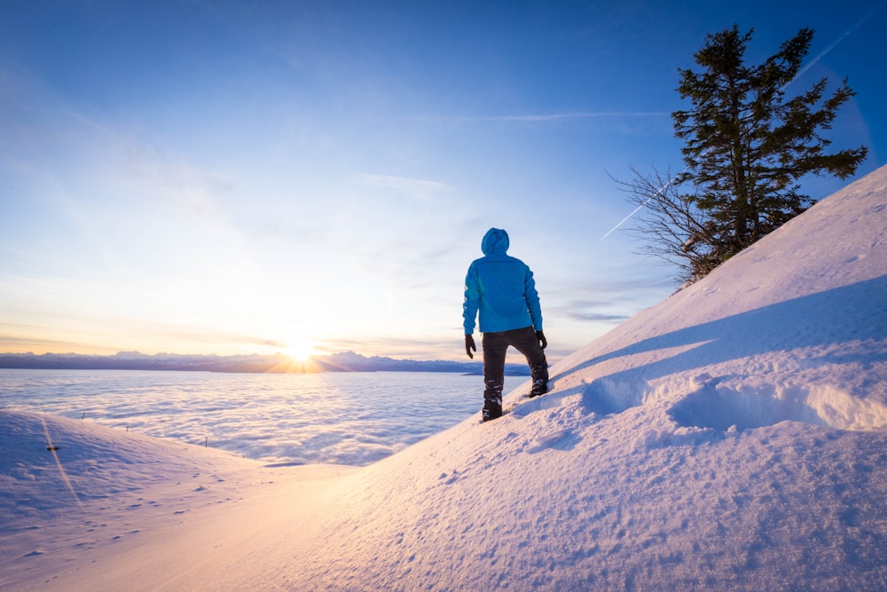 Mann in blauer Jacke, der tagsüber auf schneebedecktem Boden steht
