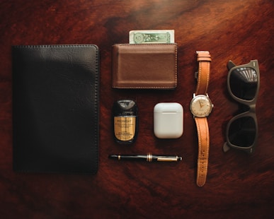 brown leather bifold wallet beside white apple airpods and white apple airpods